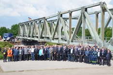 Die Besucher und Besucherinnen gemeinsam mit THW-Angehörigen vor der fertigen Brücke